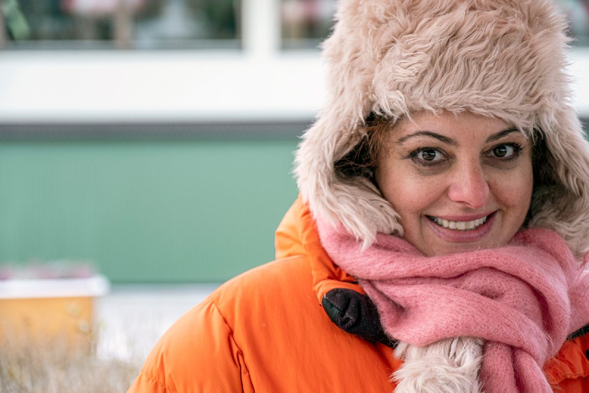 En glad kvinna i vinterkläder tittar in i kameran.